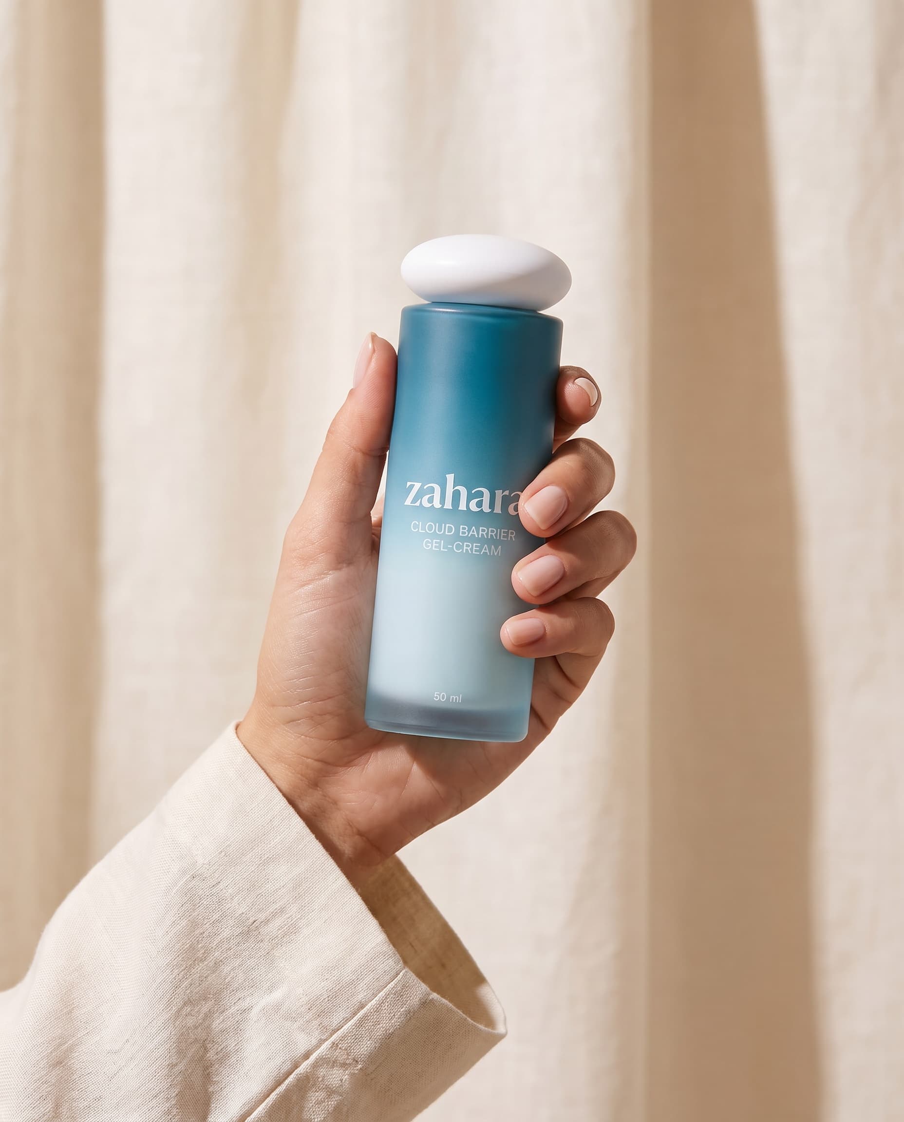 Zahara Cloud Barrier Gel-Cream held against warm ivory linen.