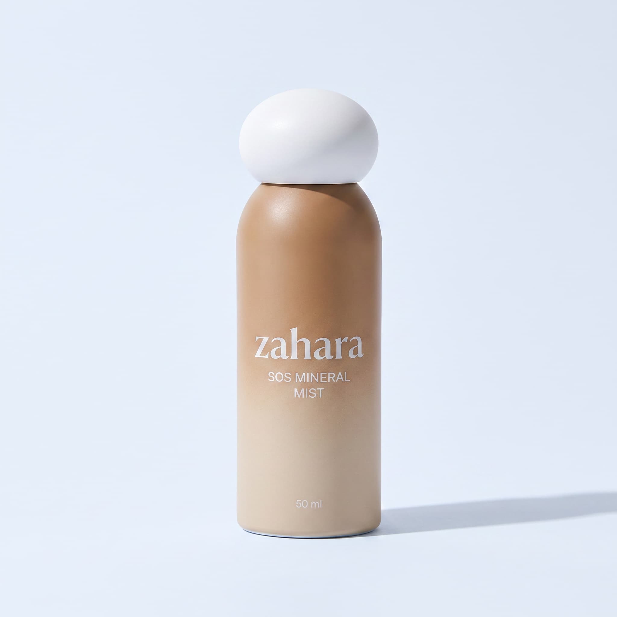 Zahara SOS Mineral Mist packshot: sand-to-bronze gradient bottle with the white pebble cap.